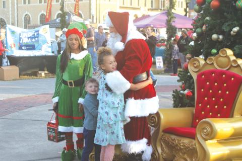 A child hugs Santa Claus at last year’s Light Up the Night Christmas Tree Celebration in Olustee Park. (FILE)