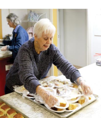 Anne Tatem covers desserts that were provided with dinner during food preparation for the cold weather shelter at Parkview Baptist Church. (TONY BRITT/Lake City Reporter)