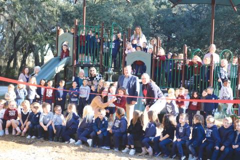 Students and staff at Belmont Academy pose for a ribbon-cutting ceremony during Monday’s debut of their new playground equipment. (TONY BRITT/Lake City Reporter)