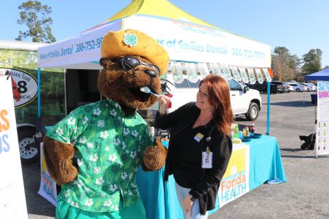 Bellamy Beaver gets his teeth brushed by Brandy Hunt, dental hygienist with the Columbia County Health Department, as the mascot visited vendor stands during Bellamy’s Big 4th Grade Field Day.  (TONY BRITT/Lake City Reporter)