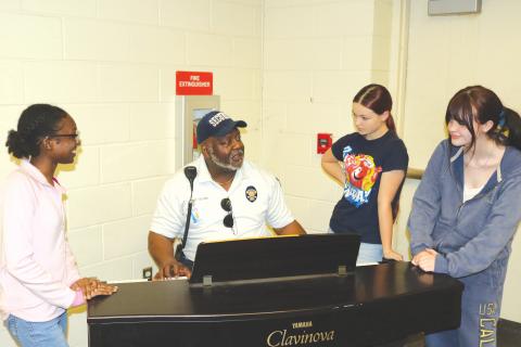 2026 Golden Voice contestant Skye Flournoy (from left) gets musical tips from Ronnie Collins, Golden Voice founder, as Aleah Rogers and Stella Jennings also take in the information. (TONY BRITT/Lake City Reporter)