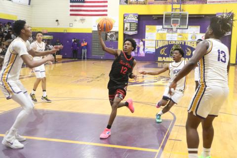 Fort White's Jonathan Bessent drives through the lane against Union County center Adrian Manns (left) and forward Tyrese Chandler during Thursday's District 6-R semifinal. (MORGAN MCMULLEN/Lake City Reporter)