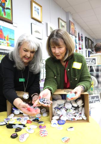 Sheri Carder (left) and Dee Etheridge have fun and share laughs while they go through a box of Freedom Rocks at the Gateway Art Gallery last month. (TONY BRITT/Lake City Reporter)