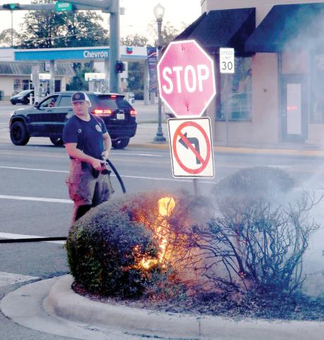 Lake City firefighter Josh Morris, uses a small hose as he prepares to extinguish shrubbery that caught fire near the Columbia County Courthouse Annex on Wednesday evening. (TONY BRITT/Lake City Reporter)