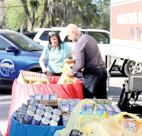 April Powell (left) and Todd Denmark, Circle of Life Assisted Living Facilities employees, unload bags of food stable items that were donated to Catholic Charities during the March Against Hunger event on Thursday afternoon. Circle of Life Assisted Living facilities contributed 1,126 canned goods to the food collection drive. (TONY BRITT/Lake City Reporter)