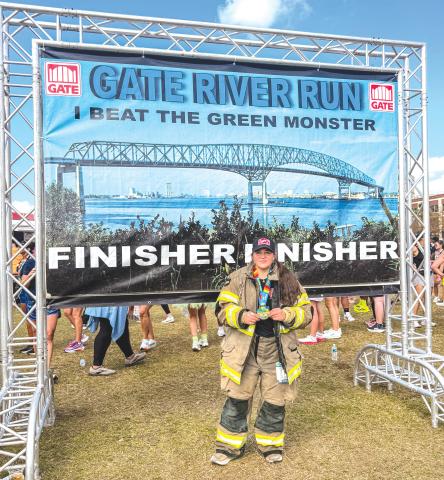 Christina Munro, a member of the Lake City Fire Department, holds her medal after finishing the Gate River Run in Jacksonville last week. Munro did the 15K run in her firefighting gear. (COURTESY)