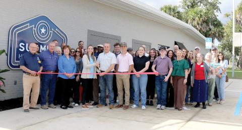 Chris Summers cut the ribbon Thursday during the grand opening celebration for Summers Home Furniture. They were joined by family, friends, employees and members of the Lake City-Columbia County Chamber of Commerce. (TONY BRITT/Lake City Reporter)