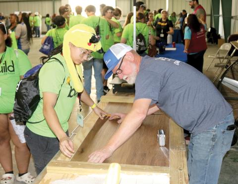 Maylianne Vazquez (left) works on connecting pieces of flooring with Eric Adams of Eric’s Flooring during Wednesday’s Build My Future event. (TONY BRITT/Lake City Reporter)