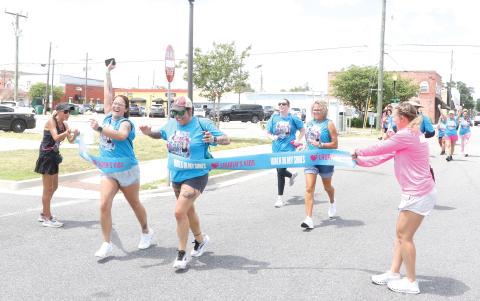 Local walkers cross the finish line in downtown Lake City on Tuesday morning after completing the eight-mile Lauren’s Kids Walk in My Shoes event. It’s the first time the statewide walk has made a stop in Lake City. (MORGAN MCMULLEN/Lake City Reporter)