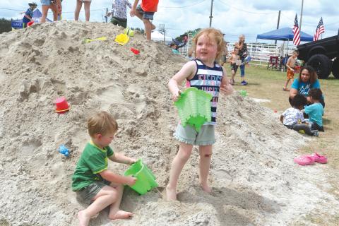 Benton Graham (left) and Lundee Graham play in a pile of sand during last year’s Kiwanis Kids Day. (FILE)