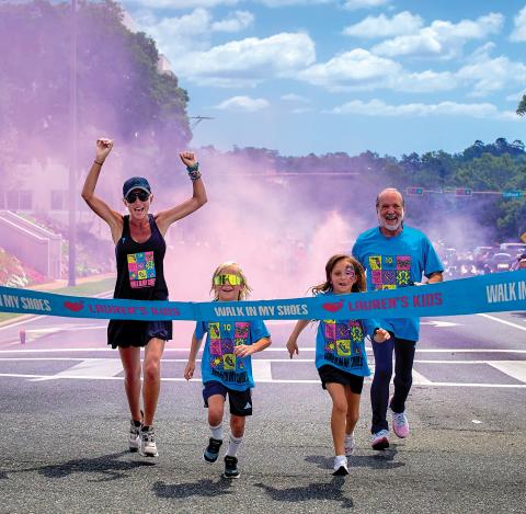 Lauren Book, a survivor and the founder of Lauren’s Kids, completes a walk at one of the stops during last year’s Lauren’s Kids Walk, along with a pair of children and her father, Ron. (COURTESY)