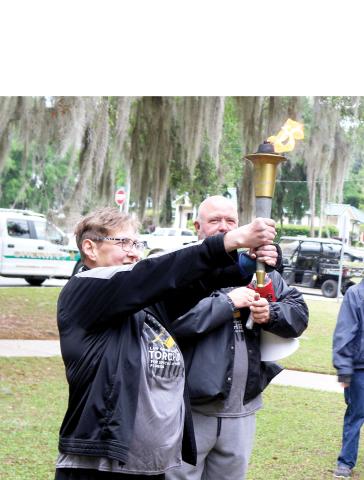 Carly Dolly, a Special Olympics athlete leader in Columbia County, served as this year’s torch bearer during Tuesday’s Special Olympics Law Enforcement Torch Run and was given the torch as it was lit by Columbia County Sheriff’s Office Sgt. Clint Dicks. (TONY BRITT/Lake City Reporter)