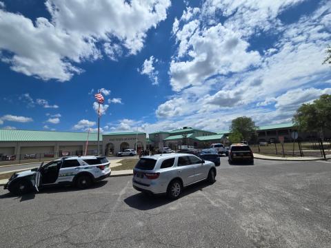 A law enforcement presence gathers near the front entrance to Fort White High School on Wednesday afternoon. The move followed an anonymous phone call to the school district that threatened student safety. (COURTESY)