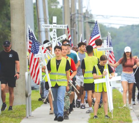 Columbia High School JROTC cadets carry flags and crosses that will be placed alongside State Road 47 in honor of veterans and first responders. (TONY BRITT/Lake City Reporter)