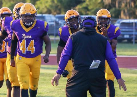Columbia defensive end Mikel Morgan (middle) races to celebrate with defensive coordinator Chris Martinez (middle) after returning a fumble for a touchdown against Camden County in Friday’s spring game. (BRENT KUYKENDALL/Lake City Reporter)