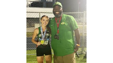 Suwannee senior Ryleigh Hermanson shows off her Class 2A state championship medal in the 1600m alongside assistant coach Twon Williams on Thursday. (COURTESY)