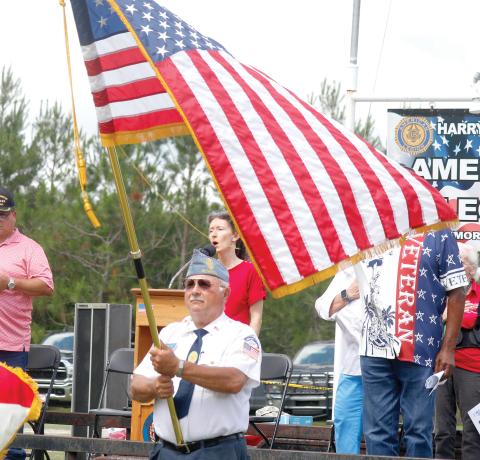Joy Geiger sings the national anthem during Monday’s Memorial Day ceremony at the American Legion Harry C. Gray II Memorial Post 107 in McAlpin as the American flag waves in front of her. (JAMIE WACHTER/Lake City Reporter)