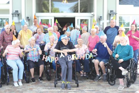 Del Porter (center) is all smiles as The Heron on Lake City residents wish him a happy 100th birthday on Thursday afternoon. (TONY BRITT/Lake City Reporter)