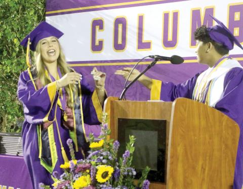 CHS Class of 2026 valedictorian Nathan Chiong (right) pays off his four-year-long $5 bet with Kadence Bates-Rogers during Friday’s commencement ceremony. (MORGAN MCMULLEN/Lake City Reporter)