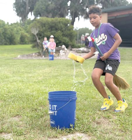 Zayden Jones learns the art of broom handling while participating in a relay race during Columbia County 4-H’s School of Life Skills for Magical Beings camp earlier this month. (COURTESY)