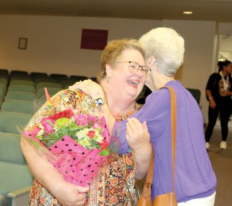 Karla Hatcher (left) gets a hug from Martha Ann Ronsonet at Tuesday’s Columbia County School Board meeting as one of five former educators honored at the district’s Teacher of a Lifetime ceremony. (TONY BRITT/Lake City Reporter)