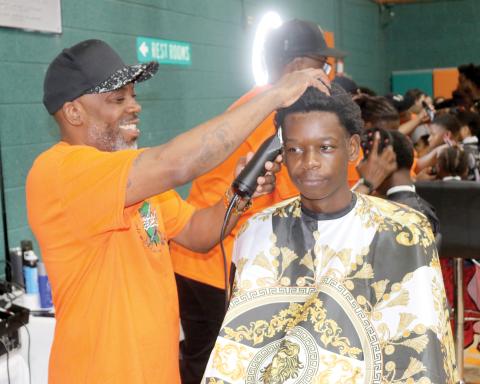 Tyrone Mullins (left), an event organizer for the Community Barbers Back-to-School Bash, gives a youngster a free haircut during last year’s event at the Richardson Community Center. (FILE)