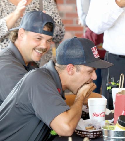 Lake City Firefighter Jerney Morgan (foreground) gets encouragement from Leon Jones as Morgan stuffs a handful ribs into his mouth during Tuesday’s rib-eating contest at Texas Roadhouse. (TONY BRITT/Lake City Reporter)