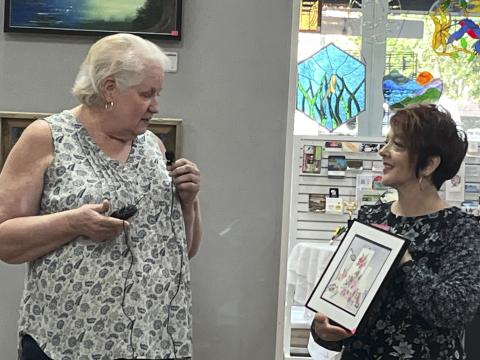 Artist Susan Guerry, of Bell, details her inspiration of her watercolor, to Gateway Art Gallery Curator Sheila Carr at the recent opening reception. She was using the terms  ‘structural chaos’ and ‘harmony’ — two seemingly opposite choices. (COURTESY)