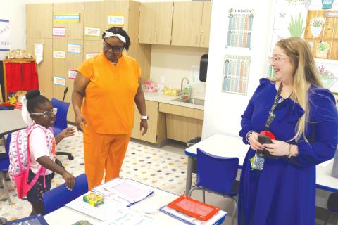 Jordynn Cray (left) prepares to get settled into the kindergarten classroom of Brittany Townsend (right) during the first day of classes at the new Eastside Elementary School. (TONY BRITT/Lake City Reporter)
