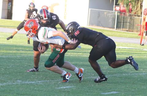 Fort White defensive linemen Josiah Harmon and Cillian Sheehan (40) tackle Eastside quarterback Cade Sutherland for a loss last Friday. (MORGAN MCMULLEN/Lake City Reporter)