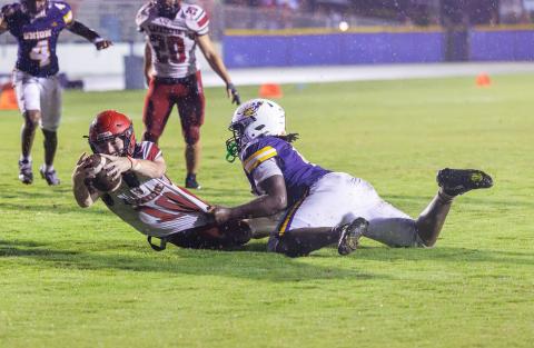 Lafayette quarterback Tucker Higginbotham stretches out for extra yards as he is wrapped up by a Union County defender Friday night. (JACK HOWDESHELL/Lake City Reporter)