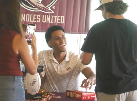 Former Florida State quarterback Jordan Travis smiles as he signs Kyler Keen's box of Cheez-Its during a meet-and-greet at the Country Club at Lake City on Thursday. (MORGAN MCMULLEN/Lake City Reporter)