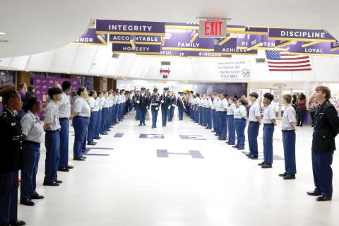 Members of the Columbia High JROTC march the American flag through the CHS commons area as other uniformed students line the walkway Friday morning for the program’s annual 9/11 Memorial March. (TONY BRITT/Lake City Reporter)