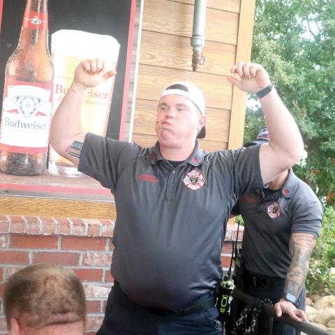 Lake City Fire Department Engineer Trenton Kreienheder raises his arm in triumph after completing his leg of the rib-eating contest Tuesday night at Texas Roadhouse. (MORGAN MCMULLEN/Lake City Reporter)