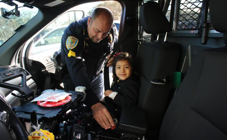 Lake City Police Department officer Robert Milligan belts in Olivia Dillow, 5, as they prepare to head out for the Lake City Police Department after a morning of shopping. (TONY BRITT/Lake City Reporter)