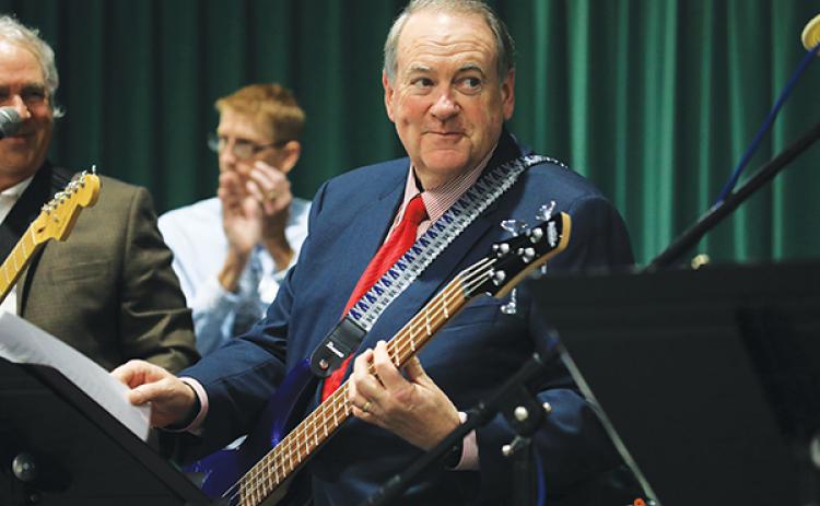 Former Arkansas Governor Mike Huckabee plays bass with local rockers Tuesday night at FGC. (CAMERON VINING/Special to the Reporter)