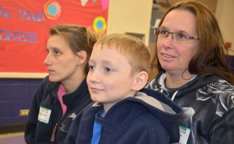 Hunter Dover, soon to turn 9, sits in his grandmother’s lap during a presentation at Five Points Elementary welcoming him back to school after a long absence. (CARL MCKINNEY/Lake City Reporter)