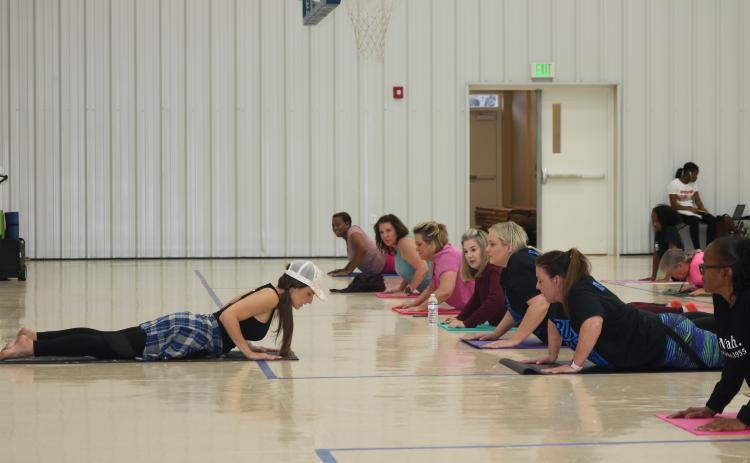 Yoga instructor Lisa Lizotte leads school district employees through stretches Tuesday afternoon in the Parkview Baptist Church gymnasium. Twenty-five people attended the first yoga class, offered as part of a school district wellness initiative. (TONY BRITT/Lake City Reporter)