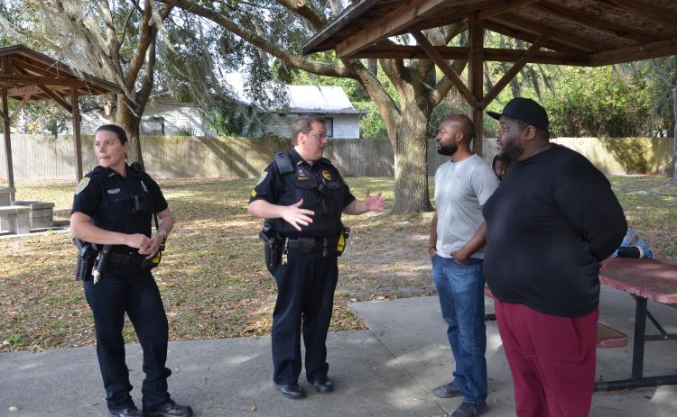 LCPD Sgt. Mike Lee speaks with Sylvester Warren and his brother, Michael Warren, after a tense exchange at a local park. Sylvester Warren gathered a group to block a public works employee from pressure washing benches, saying it would be a meaningless gesture that fails to improve the park in a meaningful way. (CARL MCKINNEY/Lake City Reporter)
