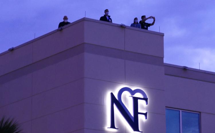 LCMC officials watch the event unfold from the hospital’s roof Sunday night. The Orchard Community Church, which organized the event, estimated that a couple hundred automobiles participated. (TRAVIS LEE/Special to the Reporter)