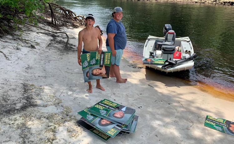 Boaters Shane McCoy and Will Griner are pictured with  the stack of signs they recovered from the Suwannee on Thursday. (COURTESY SCSO)