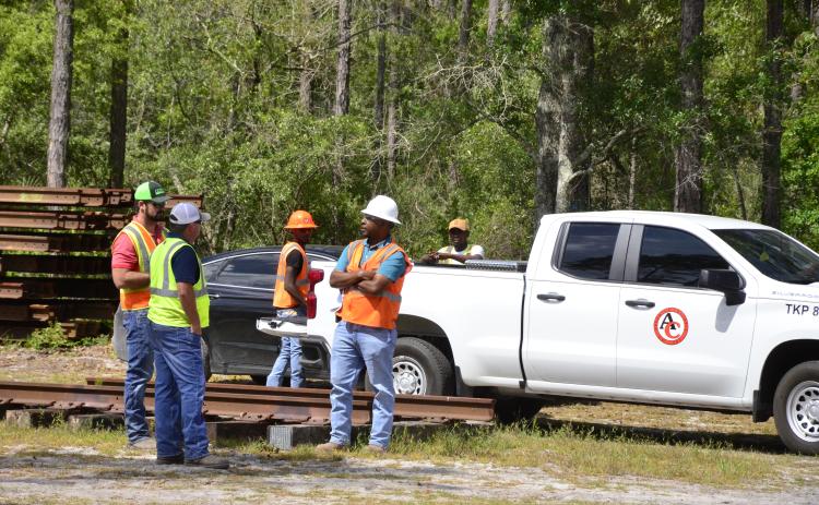 A construction crew gathers Thursday on the north side of U.S. Highway 90, where work is underway to construct a rail spur connecting the North Florida Mega Industrial Park to cities throughout the region. A stack of railing is visible in the back left. The project has been years in the making, with county officials frequently vowing it will pave the way for major economic growth in the community. (CARL MCKINNEY/Lake City Reporter)