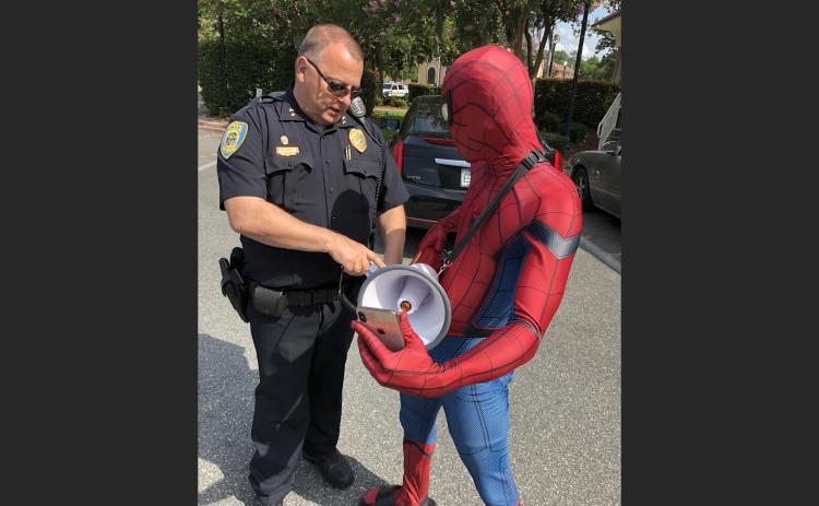 LCPD Assistant Chief Gerald Butler shows Spiderman, aka Todd Franklin, how to work the bullhorn the department lent him for a protest. (ROBERT BRIDGES/Lake City Reporter)