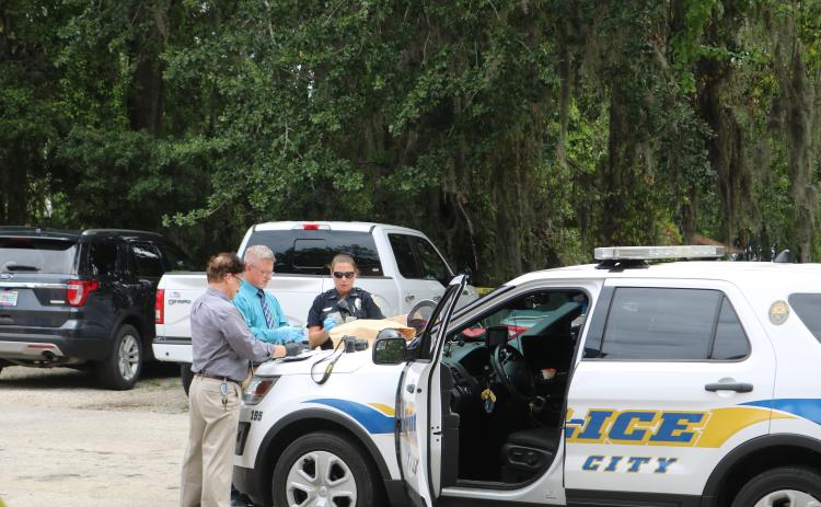 Phil Dorris, LCPD evidence technician (from left), Lt. Andy Miles and Officer Erica Bass count stolen money from the Ameris Bank robbery Wednesday morning. The loot was recovered after a suspect was apprehended about a block south of the bank. (TONY BRITT/Lake City Reporter)