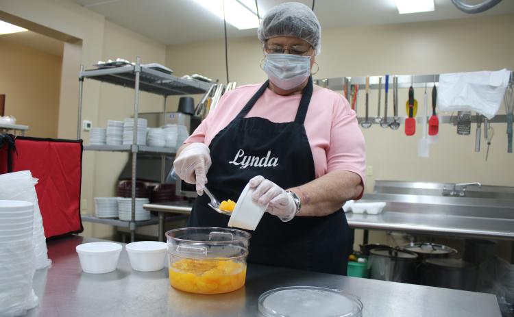Lynda Cauley spoons up some Mandarin oranges as she prepares food at the Columbia County Senior Services Lifestyle Enrichment Center kitchen. (TONY BRITT/Lake City Reporter)