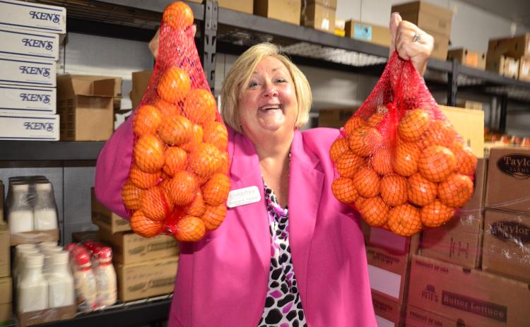 Suzanne Edwards, regional director for Catholic Charities, which operates Florida Gateway Food Bank, holds a couple of bags of oranges at the organization’s HQ on Northwest Railroad Street. (CARL MCKINNEY/Lake City Reporter)