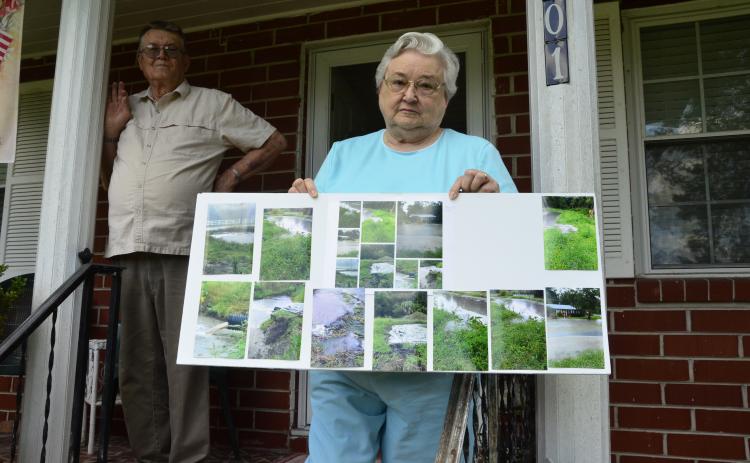 Ona and Donald Strand show pictures of the most recent flood on their property by Gwen Lake. The lakeside neighborhood’s ongoing watery woes have prompted the city to pursue a project to improve drainage in the area. (CARL MCKINNEY/Lake City Reporter)