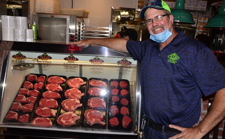Steve Hale, managing partner for the Lake City Texas Roadhouse, poses alongside an assortment of meats ahead of the opening of the chain’s new location. (CARL MCKINNEY/Lake City Reporter)
