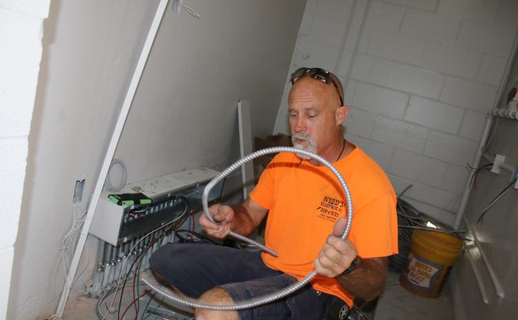 David Warren, a Wood’s Electrical Services employee, installs electrical wires in the Summers Elementary School kitchen Wednesday afternoon. The kitchen was recently gutted and will be updated for when students return to school. It’s the first major renovation project on the school’s kitchen in the past 25 years. (TONY BRITT/Lake City Reporter)