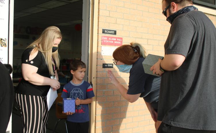 Jessica Richards (from left), a Summers Elementary School kindergarten teacher, looks on as Jayden Wilson watches his parents Ashley DeFreitas and Ryan DeFreitas wave good-bye to him on the first day of school. (TONY BRITT/Lake City Reporter)